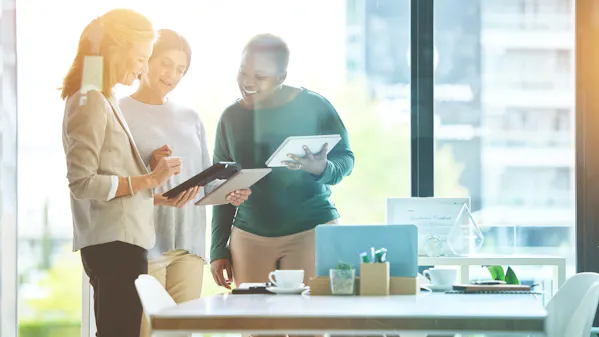 Menschen im Büro reden und schauen auf ein Tablet